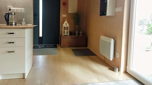 A hallway with a wooden floor, a white cabinet with drawers, a coffee maker, a small white lantern, and a radiator. - Holiday Home in Nowe Warpno by the Harbor (Nowe Warpno)