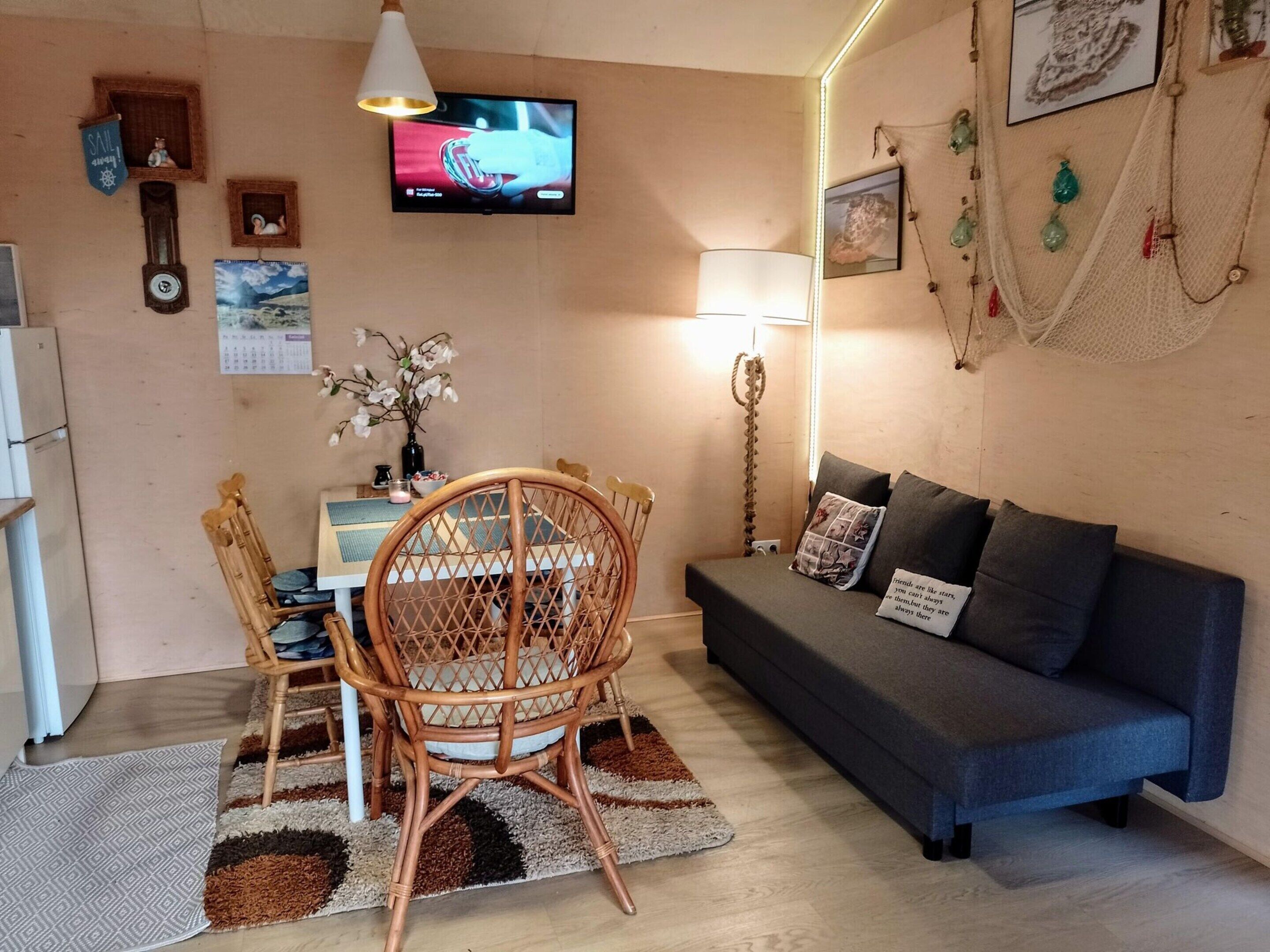 A cozy living room with a dining area, featuring a television, a sofa, and a dining table with chairs.