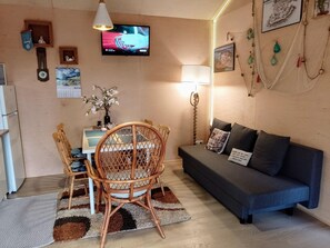 Ein gemütliches Wohnzimmer mit Essbereich, ausgestattet mit einem Fernseher, einem Sofa und einem Esstisch mit Stühlen.