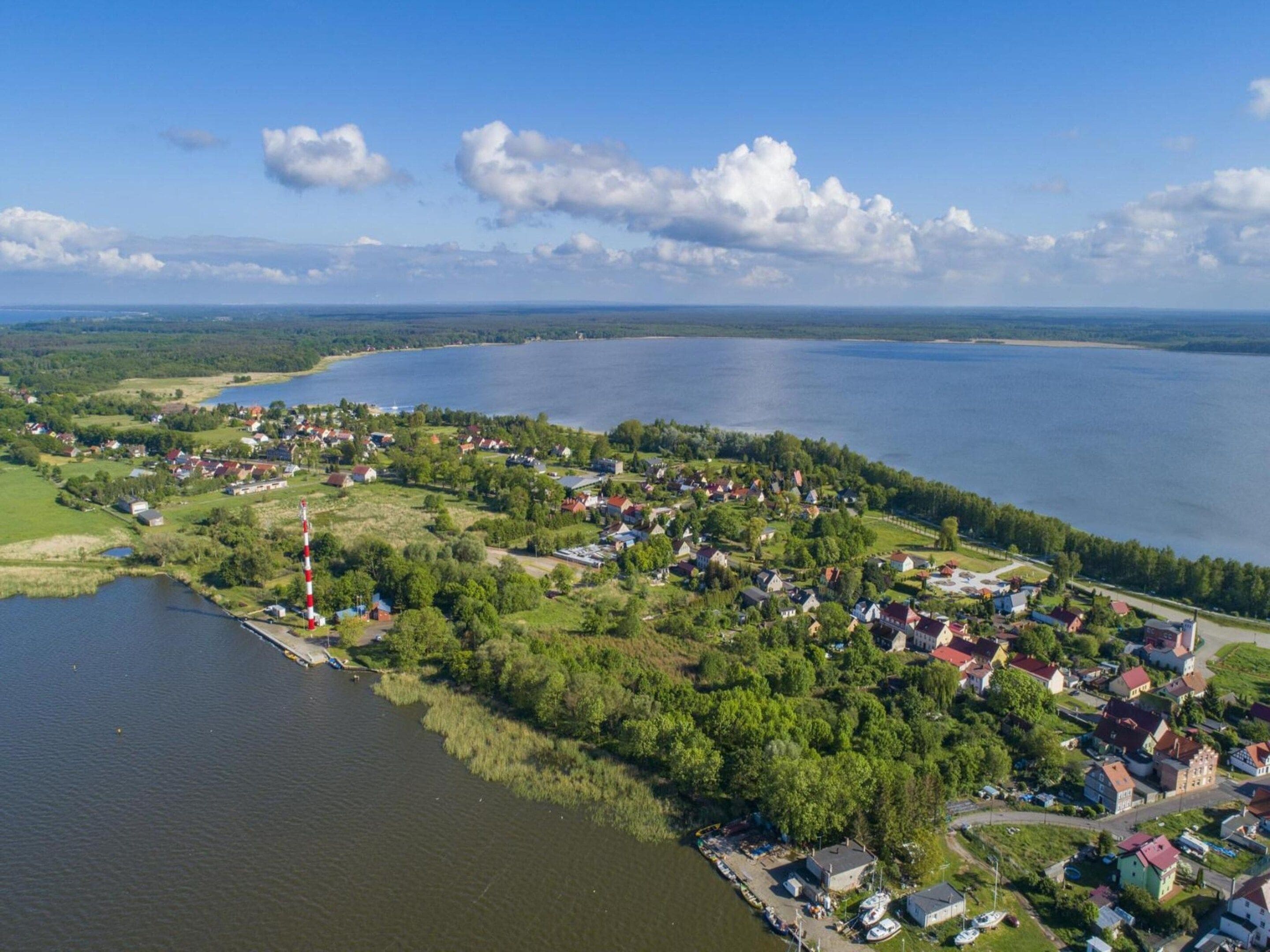 Un pueblo a orillas de un lago, con casas, un faro y barcos.