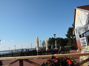 Ein Restaurant am Wasserufer mit Terrassensitzgelegenheiten, Sonnenschirmen und Blick auf das Wasser.