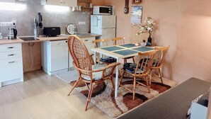 A compact kitchen with white cabinets, a microwave, and a coffee maker. There is a dining table with four chairs and a TV mounted on the wall. - Holiday Home in Nowe Warpno by the Harbor (Nowe Warpno)