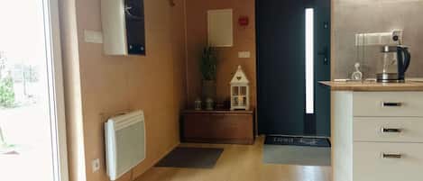 A narrow hallway with a radiator, a small plant, and a white cabinet with drawers.