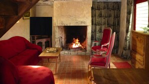 Uma sala de estar aconchegante com lareira, móveis de madeira e uma televisão.