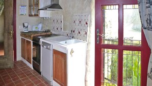Uma cozinha com uma porta vermelha, uma janela com vista para o verde e um painel de azulejos.