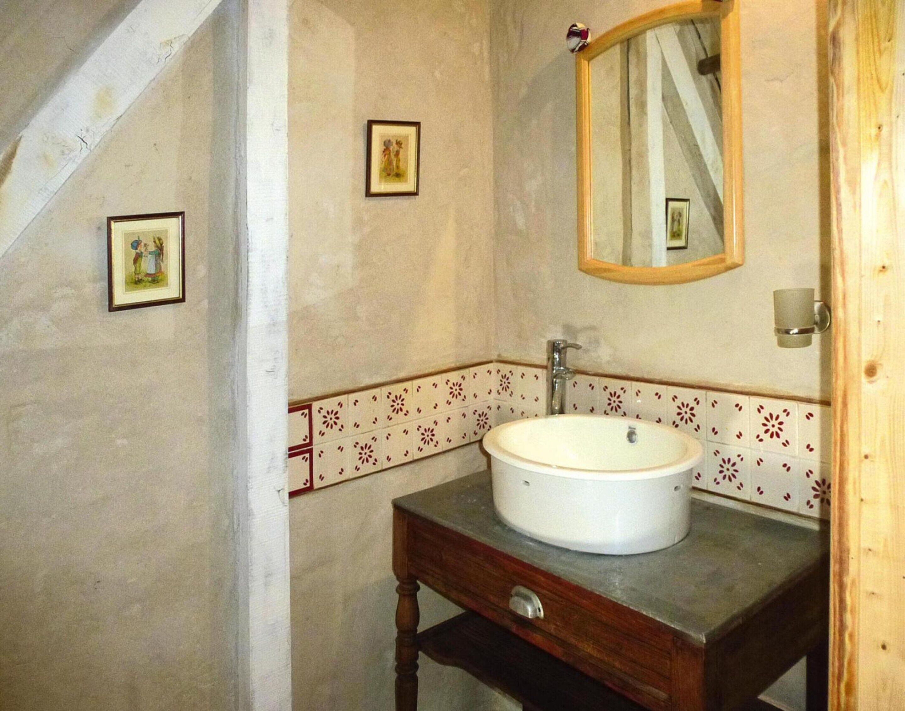 Un baño con un lavamanos redondo, un mueble de madera y un espejo.