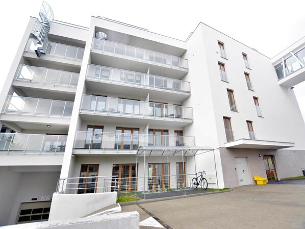 A multi-story building with balconies, a covered entrance, and a bicycle parked outside. - Apartment With Sauna in Kolobrzeg (Kołobrzeg)