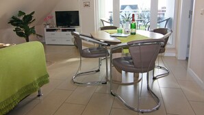 A dining area with a table, chairs, and a television in the background. - Appartementhaus Strandloper, Zinnowitz (Zinnowitz)