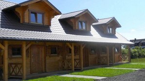 Eine Holzhütte mit geneigtem Dach, mehreren Fenstern und einer Veranda.