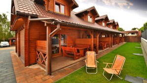 Eine Holzhütte mit einer Veranda, Sitzgelegenheiten im Freien und einem Rasen.