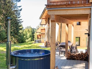 A wooden cabin with a hot tub, outdoor seating, and a stack of firewood. - Chalet Arber in St.englmar With its own Hottube (Sankt Englmar)