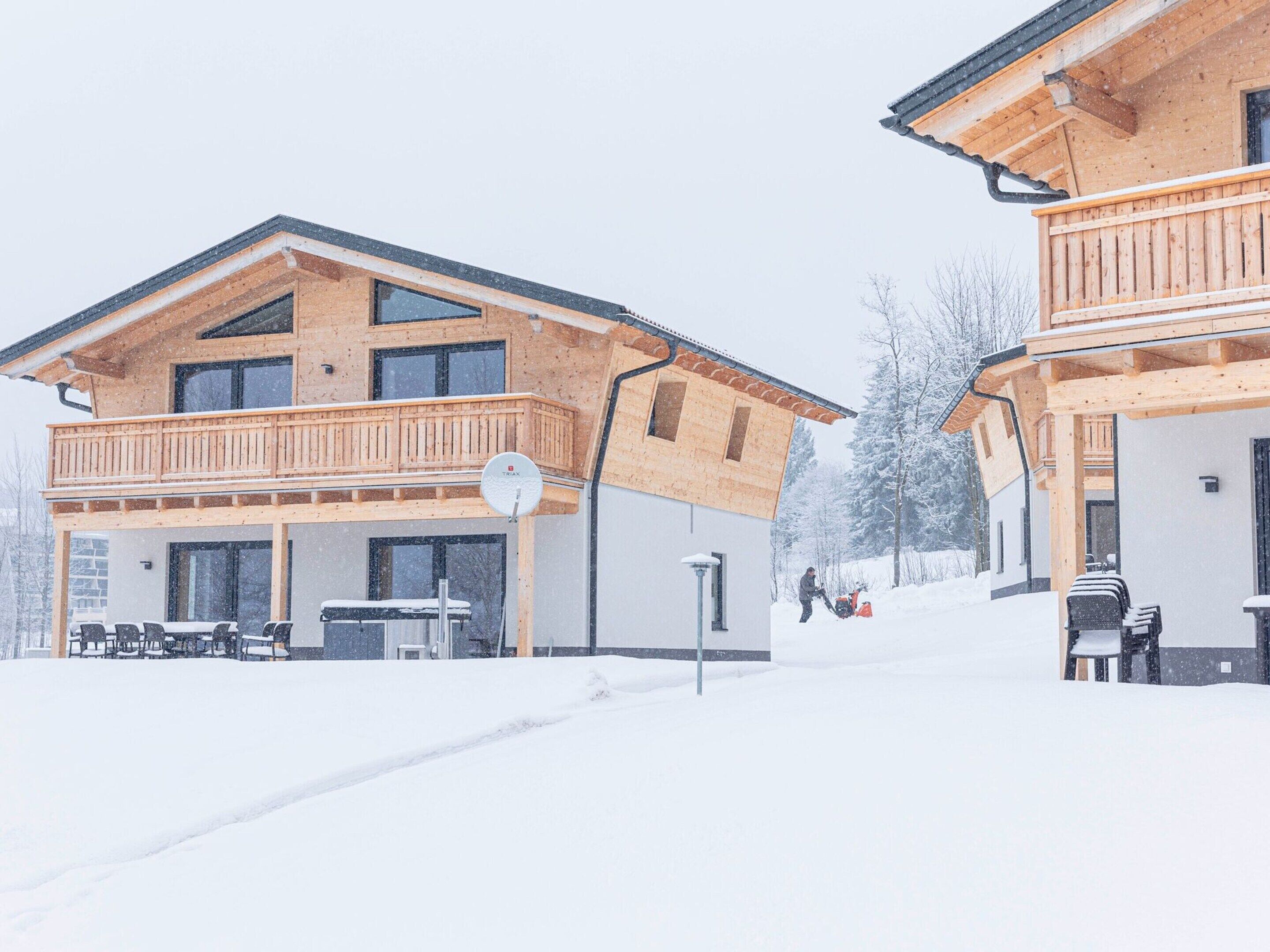 A wooden chalet-style building with a balcony and a covered outdoor seating area.