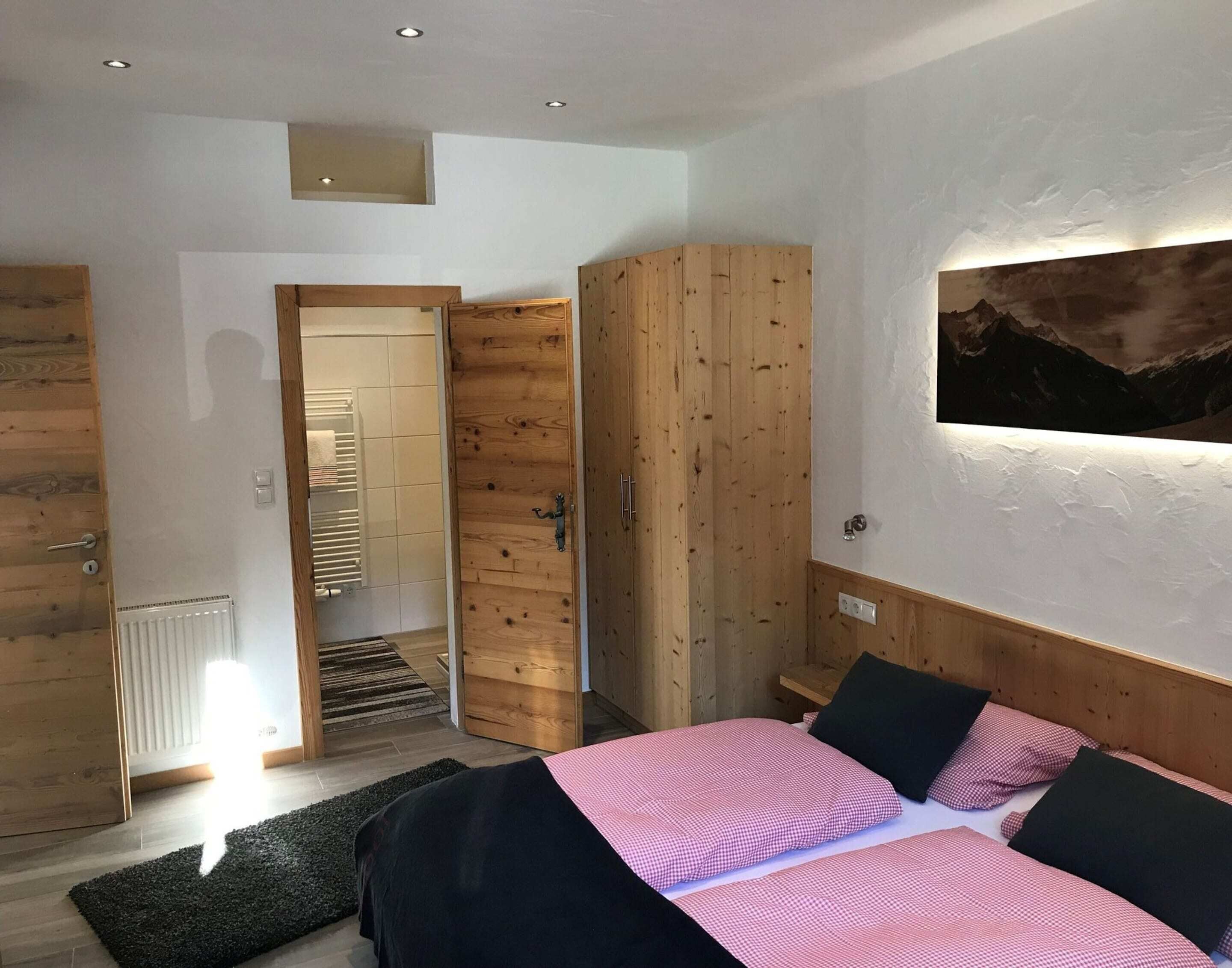 A bedroom with a bed, a wardrobe, a radiator, and a painting on the wall.