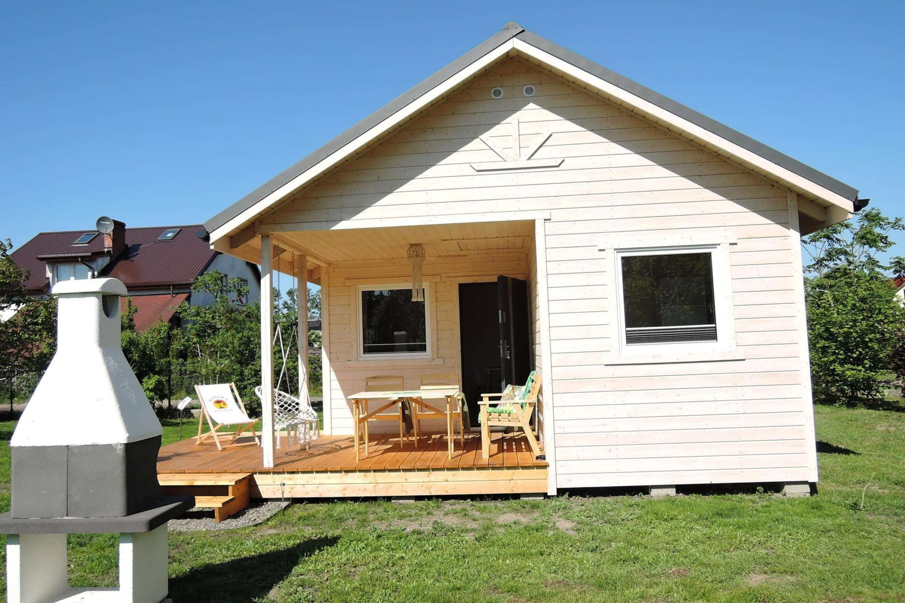 Eine kleine Holzhütte mit Veranda, Tisch und zwei Stühlen.