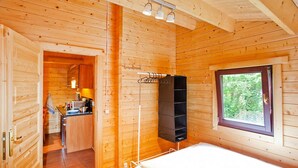 Interno di una baita in legno con un letto, una finestra vista, angolo cottura e bagno.