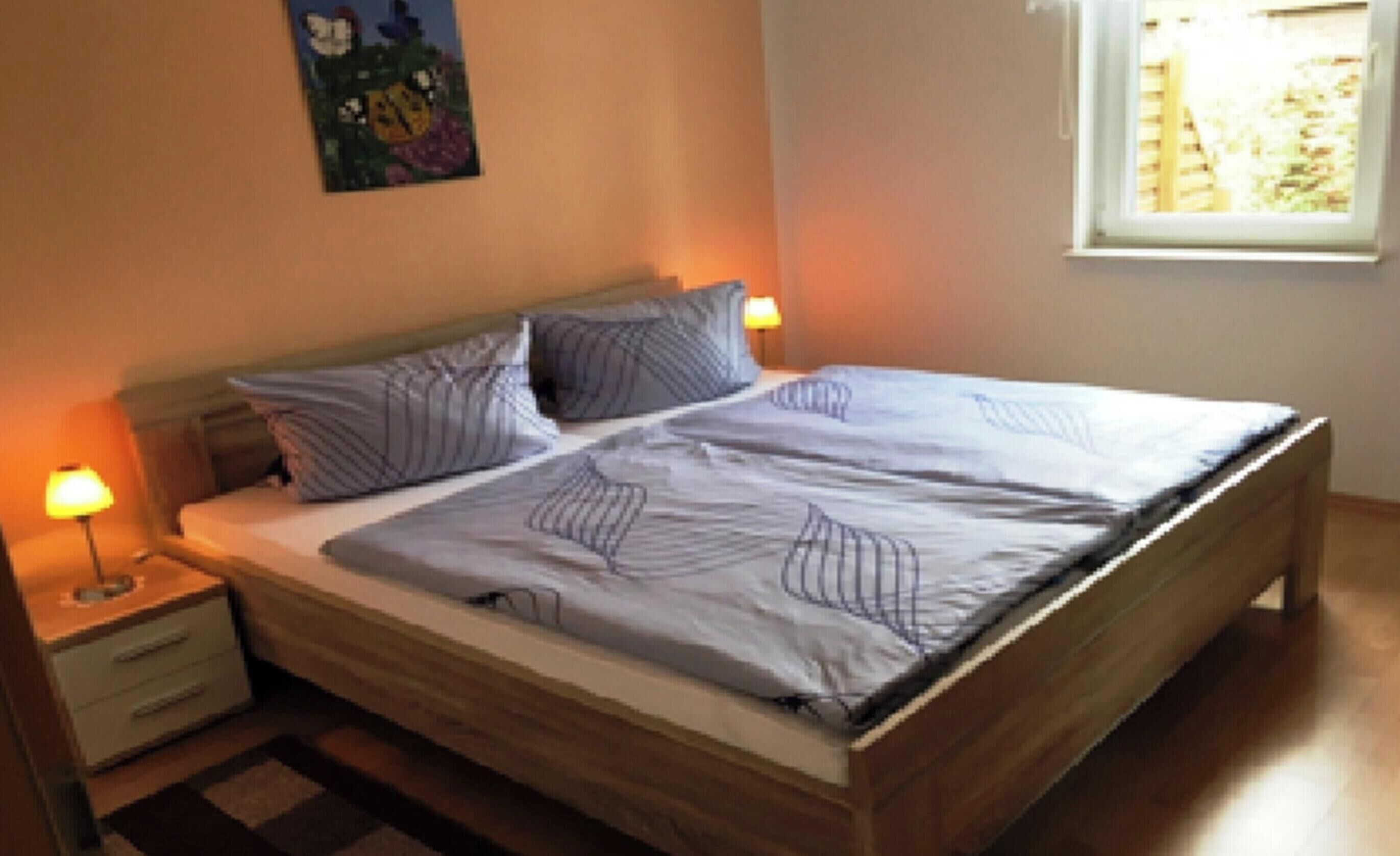 Un letto con struttura in legno, due comodini e una finestra vista.