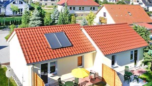 A two-story house with a red-tiled roof, a solar panel on the roof, and a patio with outdoor furniture. - Gemuetliche Doppelhaushalfte in Lubmin (Lubmin)