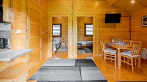Interior d'una cabana de fusta amb cuina, menjador i dues habitacions.