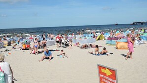 A crowded beach with people sunbathing and swimming, tents, and beach umbrellas. - House Near Baltic Sea and Wolinski Park (gmina Wolin)