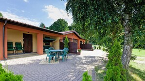 A building with a patio area featuring a table and chairs, a covered seating area, and a wooden fence. - House Near Baltic Sea and Wolinski Park (gmina Wolin)