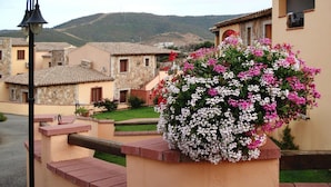 A courtyard with stone buildings, a flower planter, and a street lamp. - Apartment in Budoni With Terrace (Budoni)