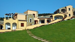 A multi-story building with a stone facade and multiple balconies. - Apartment in Budoni With Terrace (Budoni)