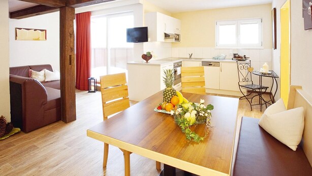 A dining area with a wooden table, chairs, and a fruit centerpiece. - Apartment in Ischgl Overlooking the Mountains (Ischgl)