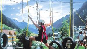 A person on a zip line course with tires and ropes, set against a mountainous backdrop. - Apartment in Ischgl Overlooking the Mountains (Ischgl)