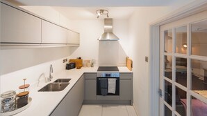 A compact kitchen with a stainless steel range hood, a double sink, and a built-in oven. - Gorgeous Garden Flat - Top Location (Cotham)