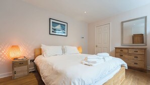 A bedroom with a bed, a nightstand, a dresser, a mirror, and a picture of Mount Fuji. - Gorgeous Garden Flat - Top Location (Cotham)