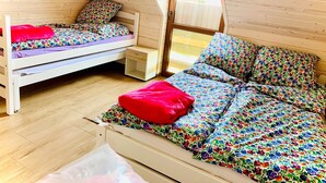 A loft-style bedroom with a bunk bed and a daybed, wooden floors, and a large window providing natural light. - Two-story Holiday Homes Close to the Seaside Beach (Mielno)