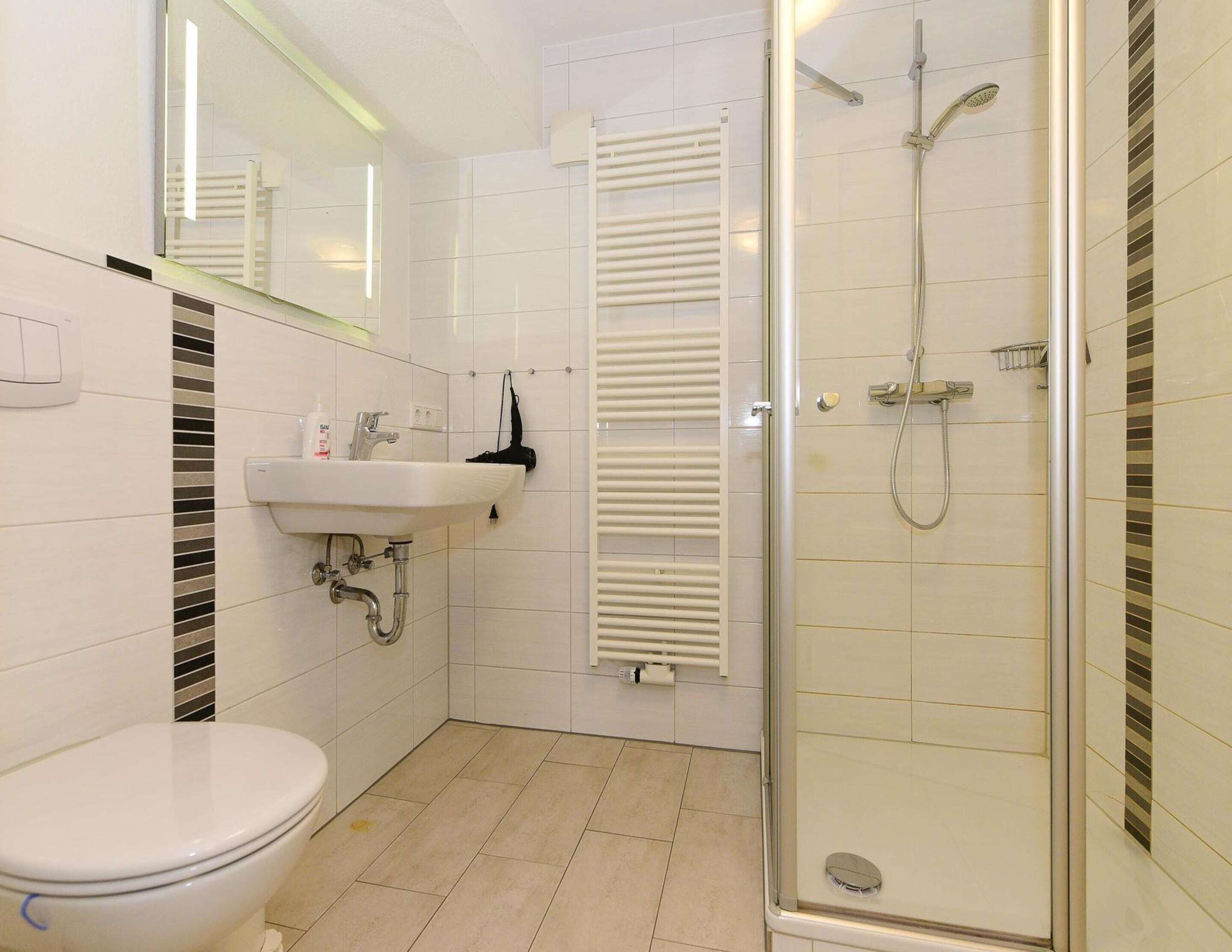 A modern bathroom with a toilet, sink, and glass-enclosed shower.