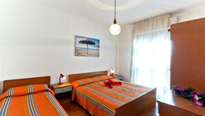 A hotel room with two single beds, a nightstand with a lamp, a wooden dresser, and a beach-themed wall art. - Residence Valbella Beach (San Michele al Tagliamento)