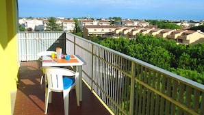 A balcony with a table and chairs, overlooking a residential area with houses and greenery. - Residence Valbella Beach (San Michele al Tagliamento)