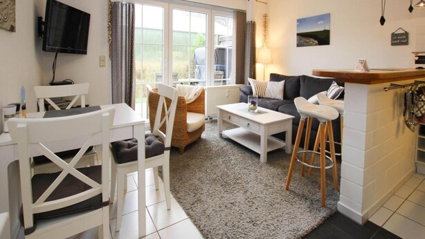 A modern living room with a dining area, a sofa, a TV, and a large window.