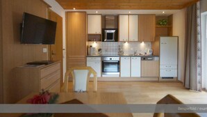 Une cuisine moderne avec des meubles en bois, un four encastré, un four à micro-ondes et un réfrigérateur.