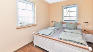 Une chambre à coucher avec un lit, deux fenêtres et un radiateur.