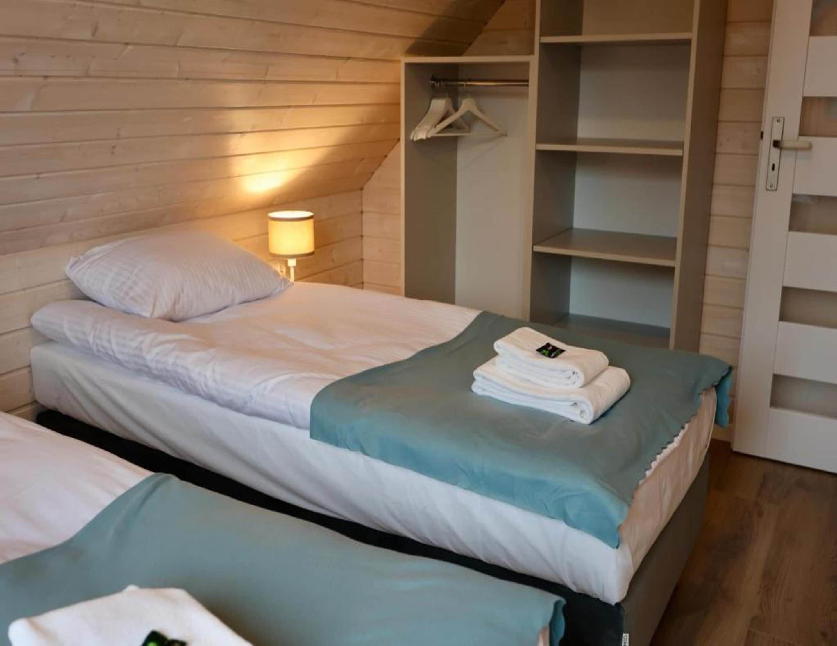 A bedroom with two beds, a wardrobe, and a hanging rack.