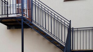 A metal fire escape attached to a building with a beige exterior. - Apartment With a Playground, Close to the Beach (Mielno)