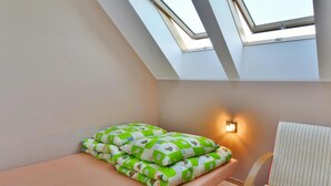 A bedroom with a skylight, a bed with green and white bedding, a bedside lamp, and a striped chair. - Apartment With a Playground, Close to the Beach (Mielno)