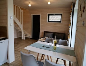 A room with a dining table, chairs, a bottle of wine, a television, and a staircase. - Holiday Home by the Beach in Stepnica (Stepnica)