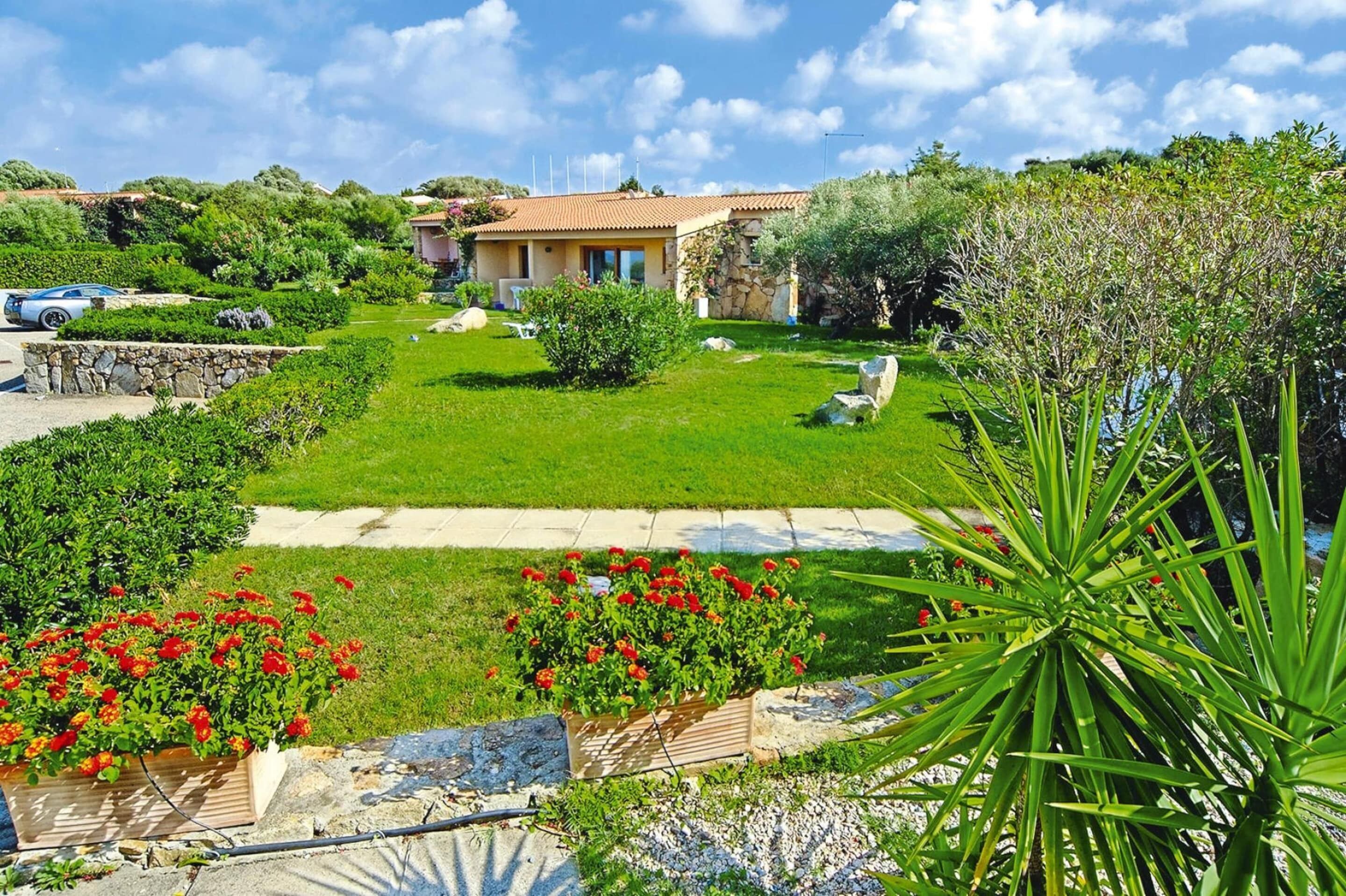 A house with a garden, a lawn, and a pathway.