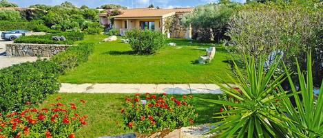 A house with a garden, a lawn, and a pathway.