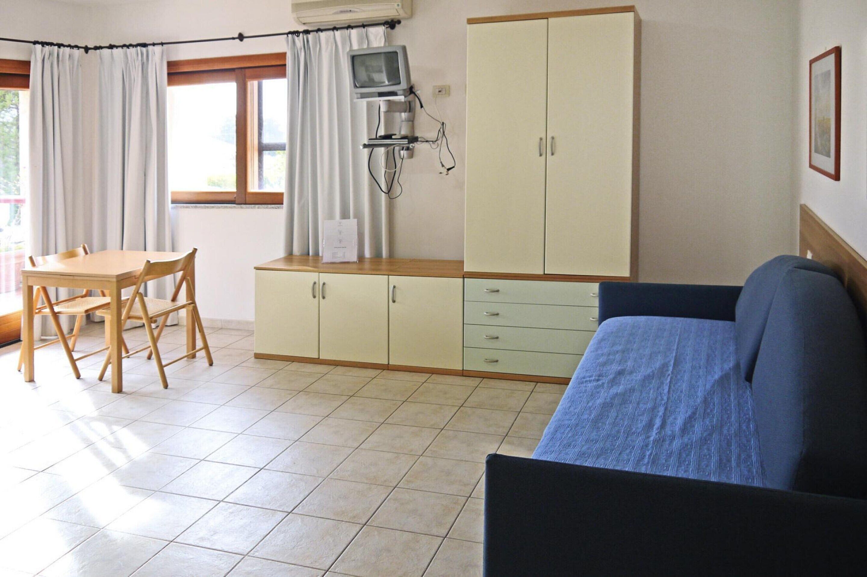 A room with a bed, a desk, a chair, and a cabinet.