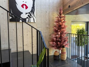 Un interior moderno con una escalera, un cuadro abstracto de gran tamaño y jarrones decorativos.