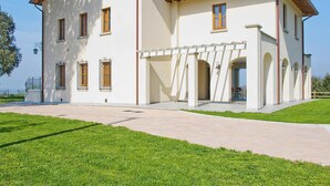 A two-story house with a white exterior, a red-tiled roof, and a covered porch with arches. - Alluring Apartment in Lamporecchio (Lamporecchio)