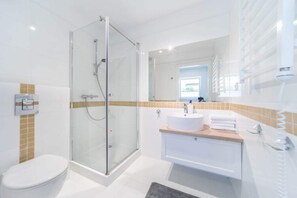 A modern bathroom with a glass-enclosed shower, a white toilet, a sink with a mirror, and a towel rack. - Holiday Cottages Close to the Beach, Pobierowo (Rewal)
