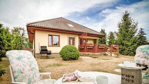 Ett hus med ett tak täckt av takpannor, en liten trädgård och en plats för grillning.