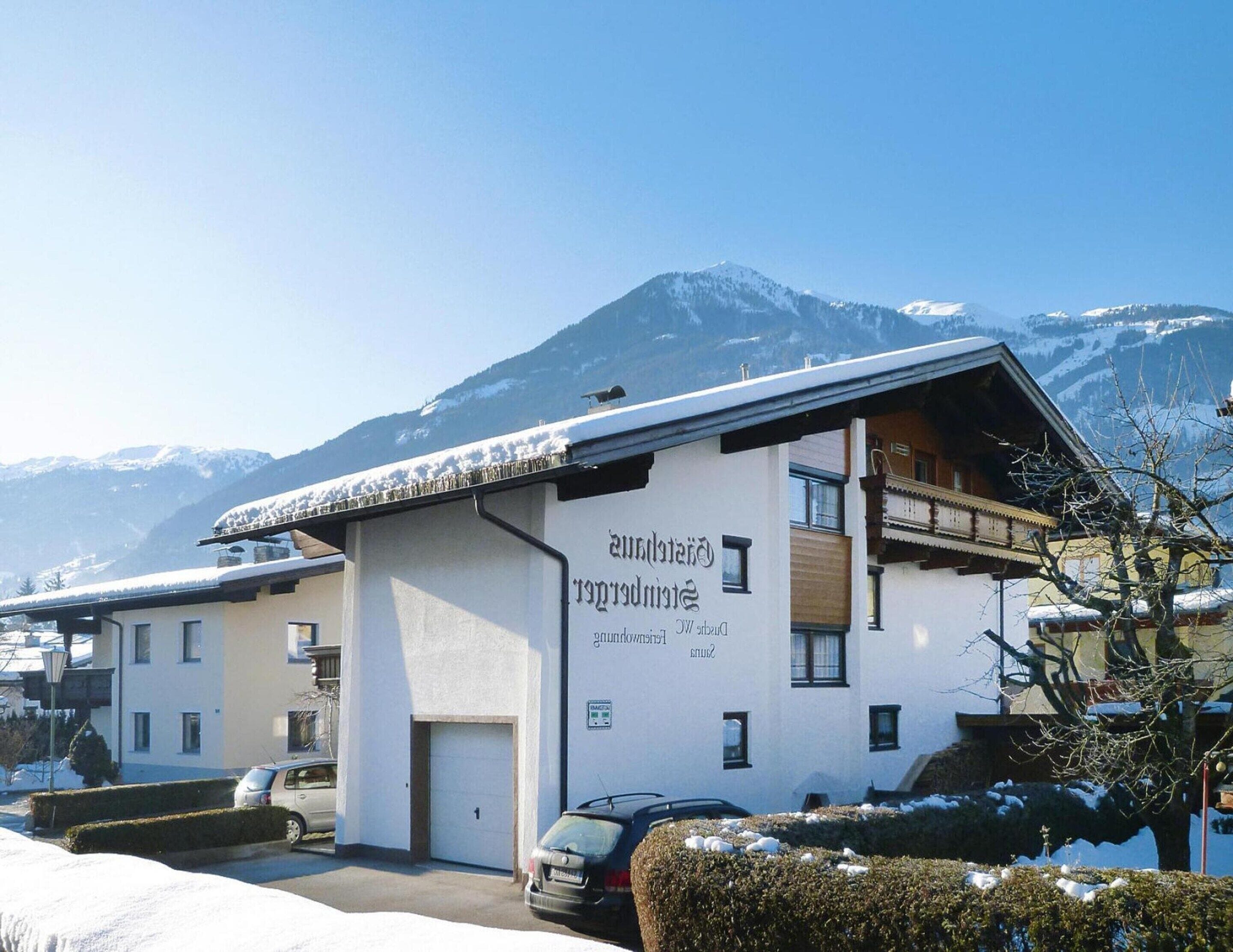 A hotel with a mountain backdrop, featuring a white exterior, a balcony, and a sign with text.