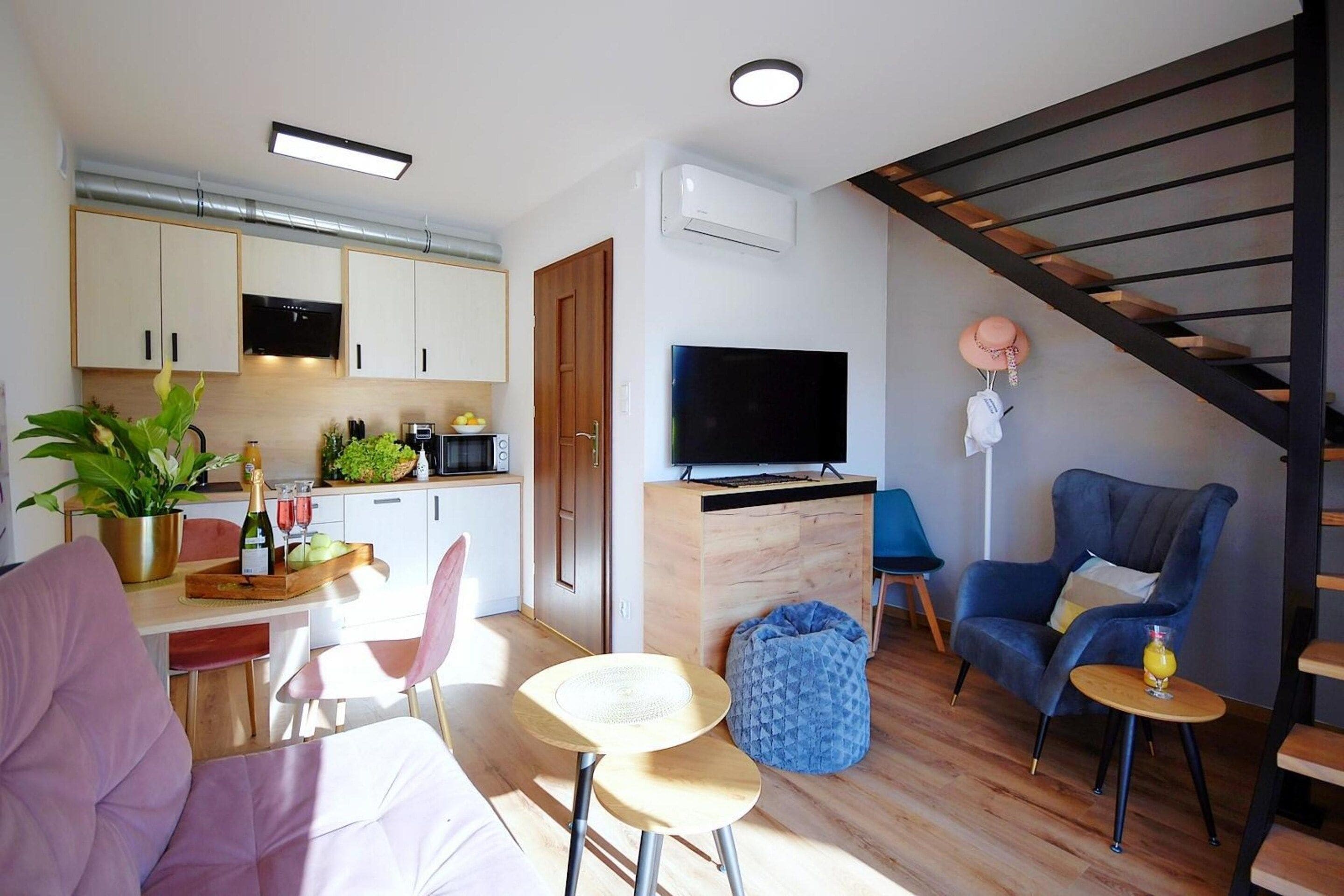 A modern living space with a kitchen, dining area, and a staircase.
